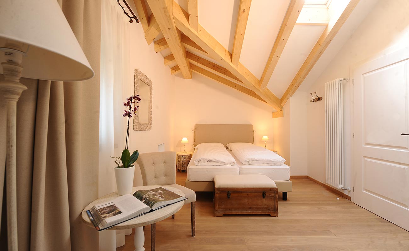 Elegante camera doppia Biancospino in legno naturale con travi a vista