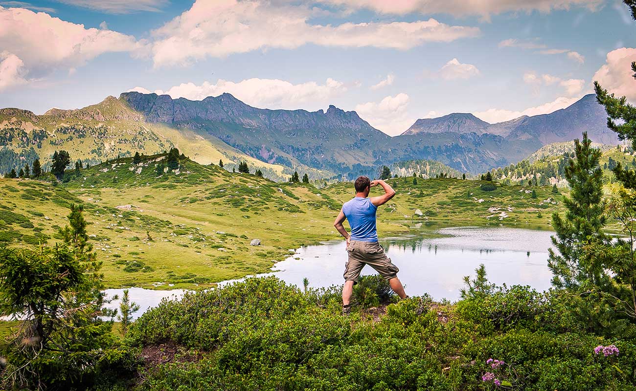 Escursionista osserva un laghetto di montagna nelle vicinanze di Borgo Valsugana
